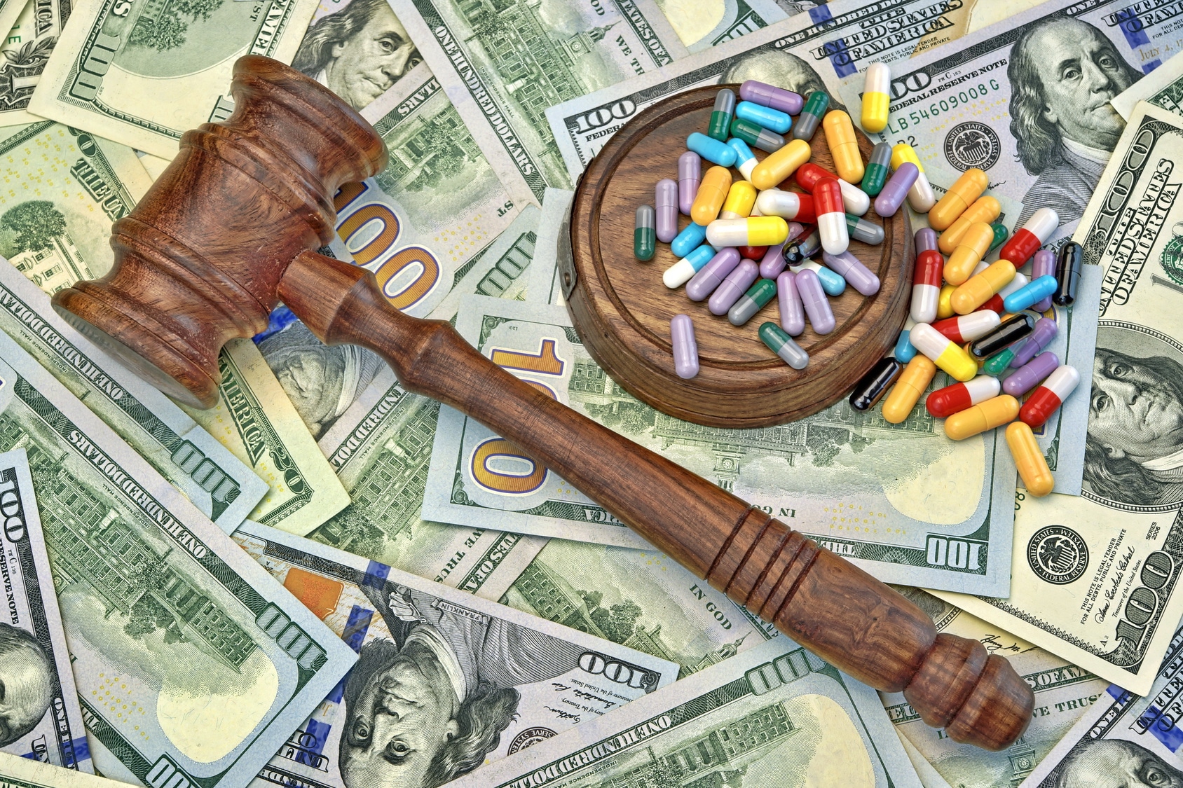 Wood Judges Gavel And Scattered Colorful Drugs On The Dollar Cash Background, Overhead View, Concept For Medical Negligence, Bail, Monetary Compensation, Drugs Falsification